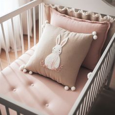 a white crib with two pillows on top of it and a bunny pillow in the middle