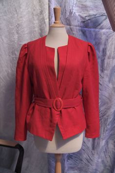 Deep red 1980s jacket or blazer with 1940s flair * made from a soft wool fabric * deep v-shaped neckline with pleated detail * single snap button in the front * puffed shoulders * fully lined * comes with a matching belt Shoulder seam - shoulder seam: 40cm / 15.5" Armpit - armpit: 46cm / 18" Waist (flat): 44cm / 17.5" Sleeve length: 60cm / 23.5" Length: 57cm / 22.5" All purchases are final unless I have made a significant error in the description of an item. All my items are vintage and thus wil Vintage Red V-neck Outerwear, Red V-neck Blazer For Workwear, Red V-neck Blazer For Work, 1980s Jacket, Cosplay Ideas, Soft Wool, Wool Fabric, Red Jacket, Wool Jacket