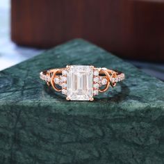 an emerald colored diamond ring sitting on top of a green marble slab