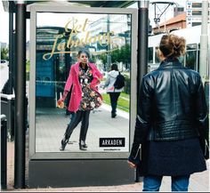 an advertisement for a women's clothing store on the side of a bus stop