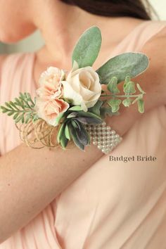 a woman wearing a pink dress holding a bouquet of flowers and greenery on her arm