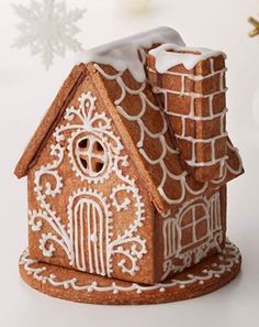 a gingerbread house with white icing on it's roof and snowflakes in the background