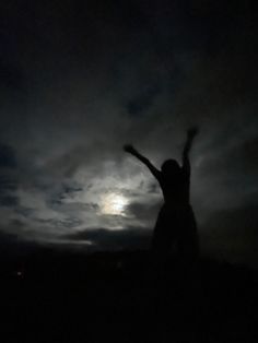 a person standing in the dark with their arms up