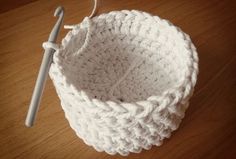 a white crocheted basket with a knitting needle