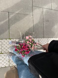 a person sitting on the ground with flowers in their lap and one hand holding something