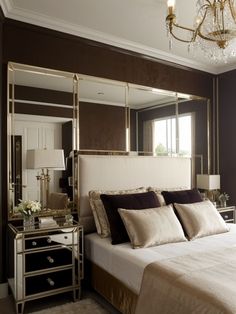 a bedroom with a bed, mirror and chandelier