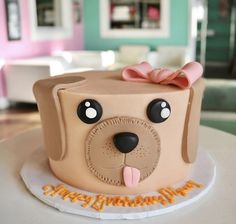 a cake shaped like a dog with a pink bow on it's head and ears