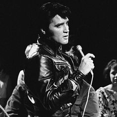 elvis presley singing into a microphone while standing next to other people in black and white