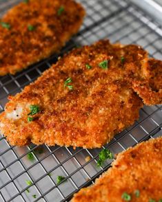 three pieces of fried fish on a cooling rack with parsley sprinkled on top