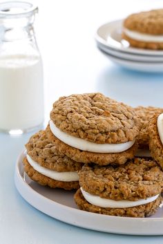 cookies with marshmallows are stacked on a plate next to a glass of milk