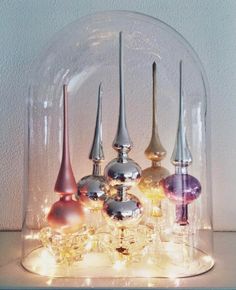 a glass dome filled with lots of different colored vases on top of a table