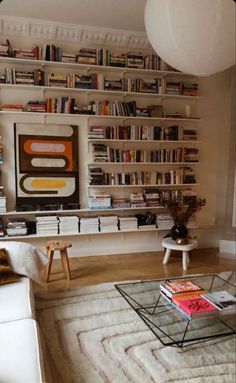 a living room filled with furniture and bookshelves next to a white couch in front of a window