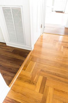 an empty room with hard wood flooring and white walls, next to a heater