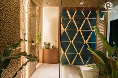 a bathroom with a blue and gold patterned wall next to a plant in the corner