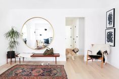 a living room filled with furniture and a large round mirror on the wall above it