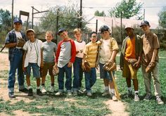 a group of young men standing next to each other on top of a grass covered field