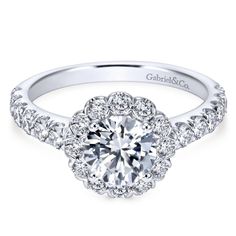 a white gold engagement ring with round diamonds on the band and an intricate halo setting