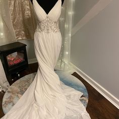 a white wedding dress on display in front of a window with lights around it and a fireplace