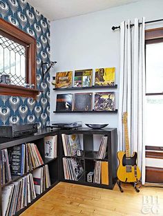 a room with a guitar, record player and various records on the shelves in it