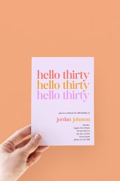 a person holding up a card with the words hello thirty written in different colors on it