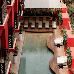 an aerial view of a pool with lounge chairs next to it and red buildings in the background