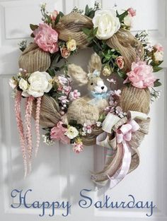 a wreath with flowers and a stuffed animal hanging from it's side on a door