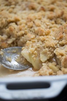 a close up of a spoon in a casserole dish with crumbs