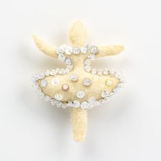 a stuffed animal with pearls and jewels on it's head is sitting in the shape of a starfish