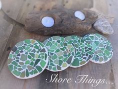 there are four green and white coasters on the wooden table next to a rock