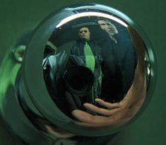 the reflection of two men in a shiny metal object that is reflecting their image on it