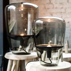 two glass vases sitting on top of tables