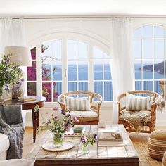 a living room filled with lots of furniture and large windows overlooking the ocean in front of them