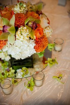 a glass vase with flowers in it sitting on a table top next to a candle holder