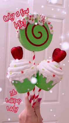 a hand holding two green lollipops with white frosting and strawberries