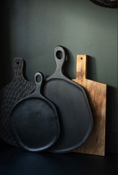 two cast iron pans are hanging on the wall next to a cutting board and knife