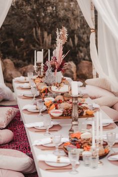 a table set up with plates and candles for an outdoor dinner or brunch