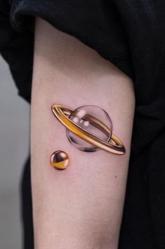 a small tattoo on the arm of a woman with an saturn symbol and two planets