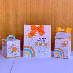 three small boxes with bows on them sitting on a table next to some paper bags