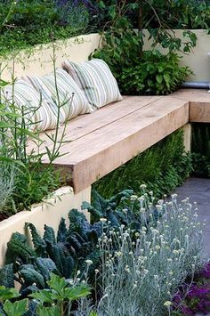 a wooden bench surrounded by plants and flowers