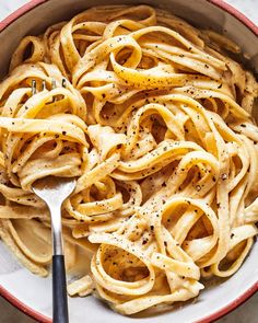 a bowl filled with pasta and topped with parmesan sprinkles next to a fork