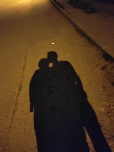 the shadow of two people standing in the street