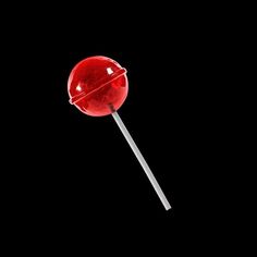 a red lollipop on a black background with the light reflecting off it's side