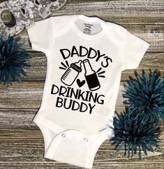 a white baby bodysuit with the words daddy's drinking buddy printed on it