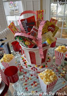 a table topped with popcorn buckets filled with candy and candies on top of it