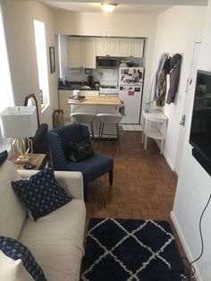 a living room filled with furniture and a flat screen tv mounted on a wall next to a kitchen