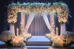 a wedding ceremony with candles and flowers on the stage decorated with white draping