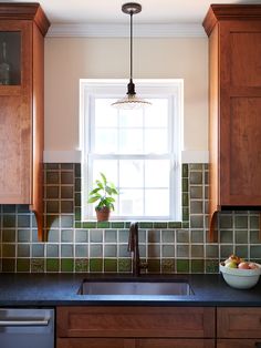 a kitchen with wooden cabinets and green tile backsplash, window above the sink