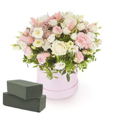 a pink and white flower arrangement in a pink box next to two blocks of soap