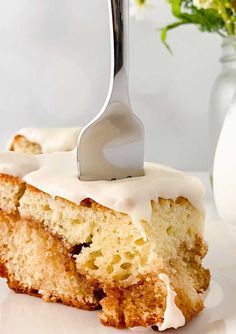 a piece of cake with white frosting and a fork sticking out of it on a plate