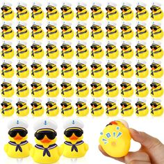 a hand holding a yellow rubber duck with sunglasses on it's head